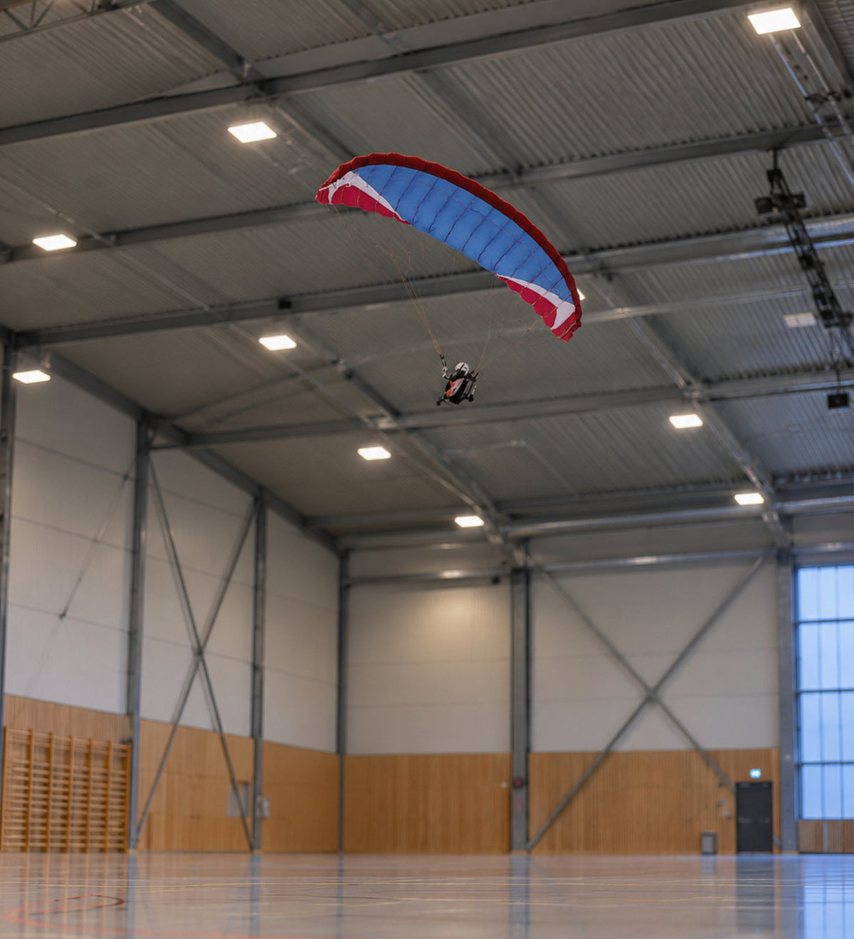 RC-Gleitschirm in Rot, Weiß und Blau beim Hallenflug in einer Sporthalle