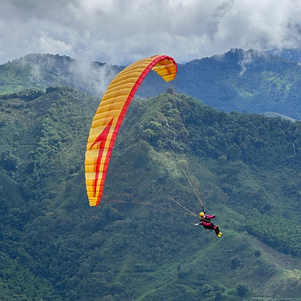 RC Paraglider Stable 2.1 Race Rast mit Pilotin Anna Free fliegt vor einer Bergwald Kulisse