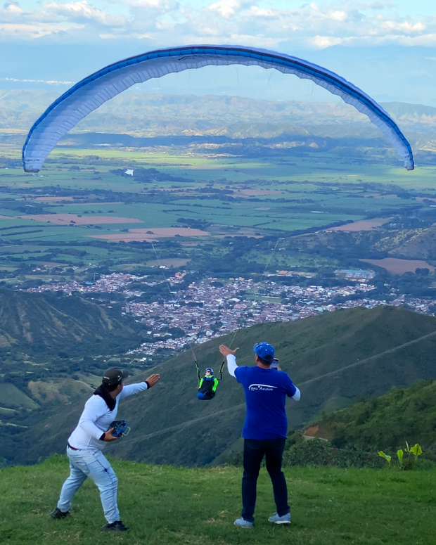 RC Gleitschirm landet in den Händen von 2 RC Piloten am Hang. Im Hintergrund ein Tal in Kolumbien